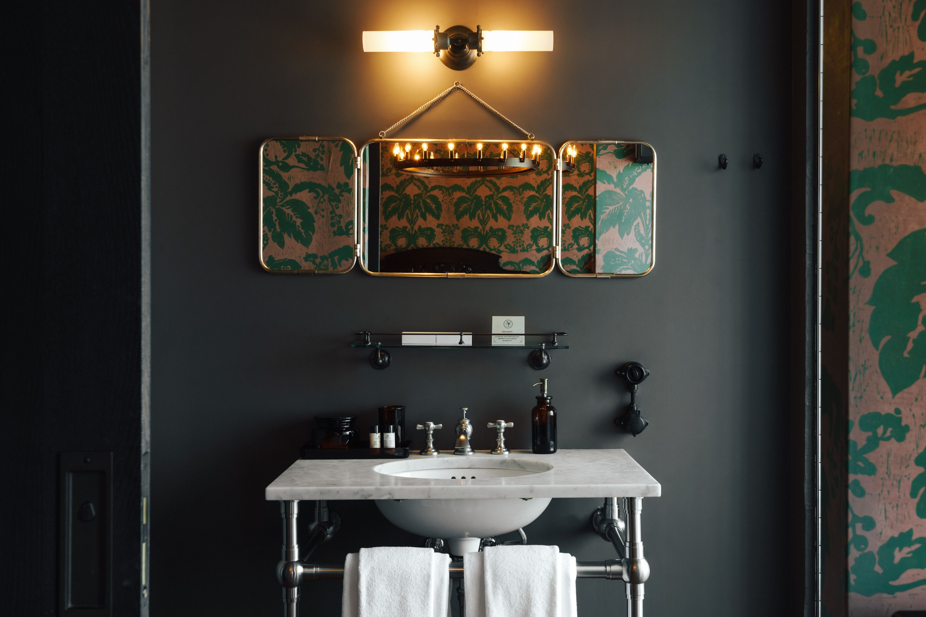 A bathroom with a large mirror, a sink, and a vanity with toiletries.