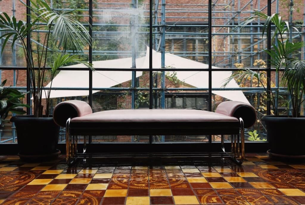A bench in a room with a checkered floor and large windows.