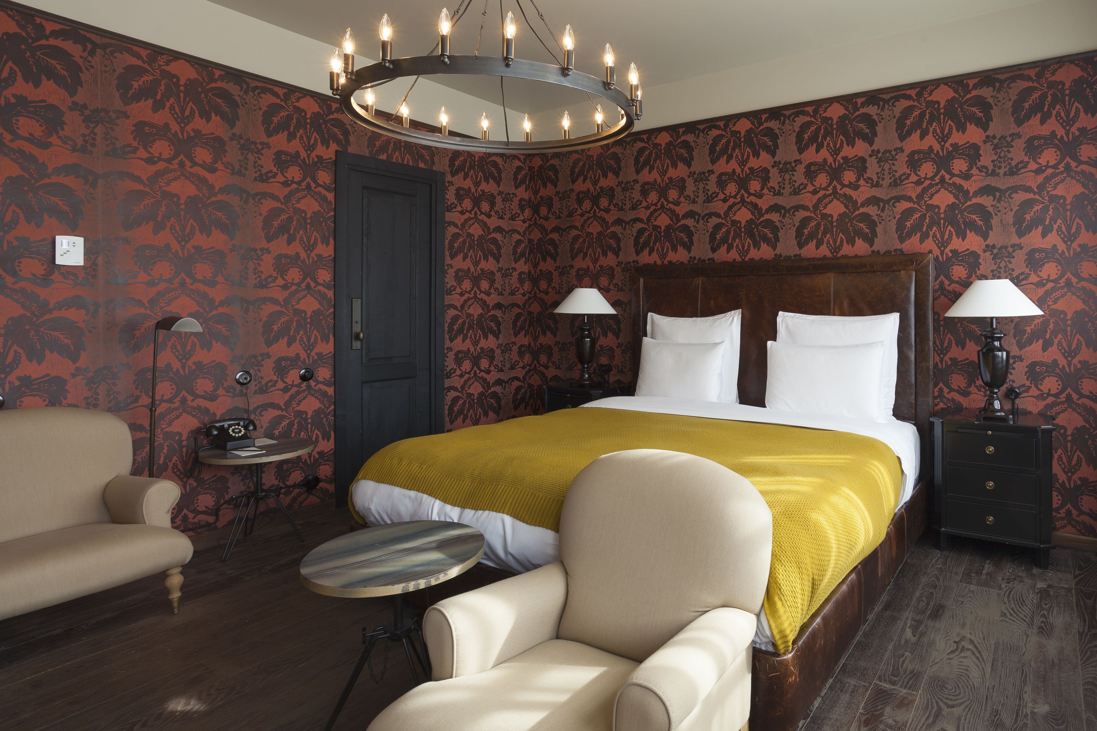 Ein Hotelzimmer mit einem großen Bett, zwei Nachttischen, einem runden Tisch, einer Couch und einem Sessel.