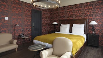 Ein Hotelzimmer mit einem großen Bett, zwei Nachttischen, einem runden Tisch, einer Couch und einem Sessel.