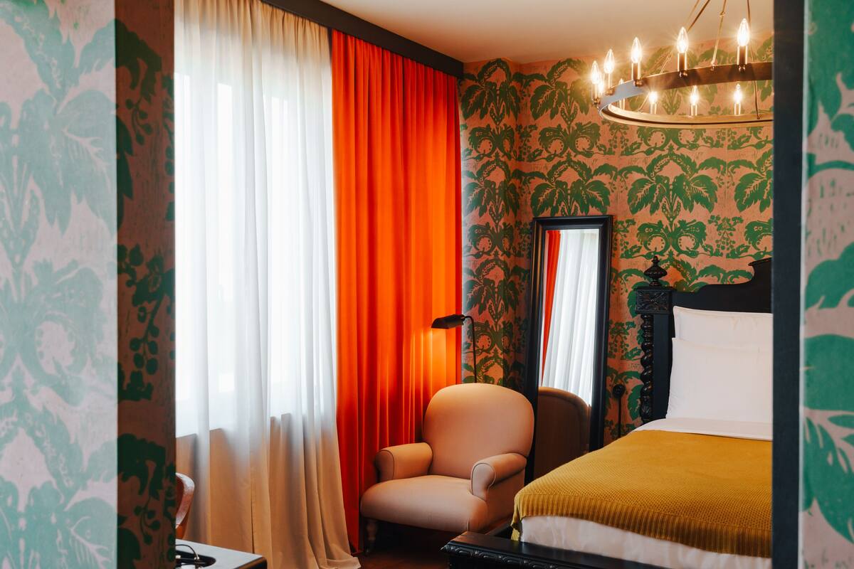 A hotel room with a bed, a chair, and a desk.