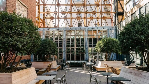 Un espace extérieur aménagé en terrasse, avec des bancs, des tables et des chaises en bois.