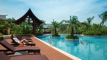 Relax by the serene pool surrounded by lush greenery and palm trees.