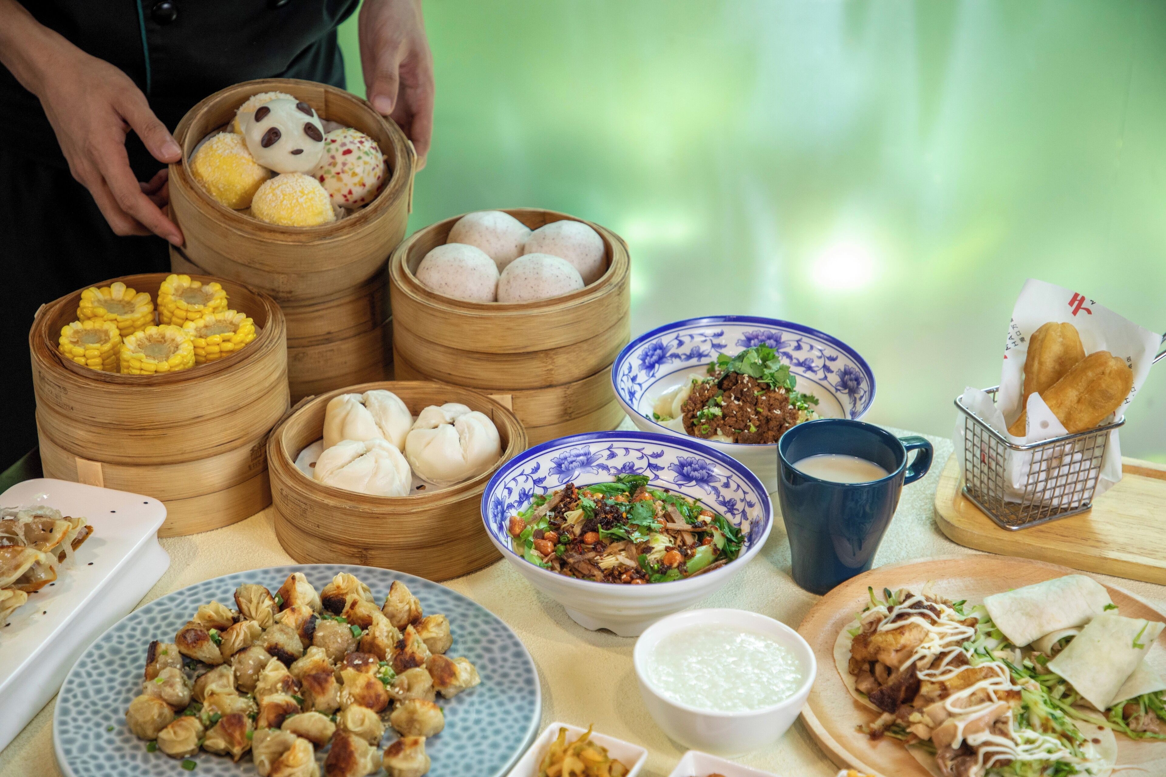 A variety of food items including dumplings, buns, and a bowl of salad on a table.