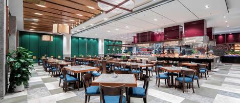 A spacious dining area with multiple tables and chairs, a central bar area, and a check-in counter.