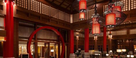 Un hall espacioso con arquitectura de madera tradicional, detalles en rojo y varias zonas de estar.