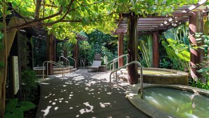 A wooden deck with a hot tub, surrounded by lush greenery and a pergola structure. - Haikou Marriott Hotel (Haikou)