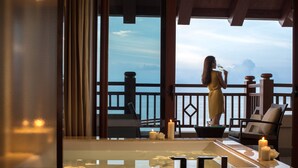 A woman in a yellow dress standing by a balcony with a view of the sea, a bathtub with candles, and a chair. - Haikou Marriott Hotel (Haikou)