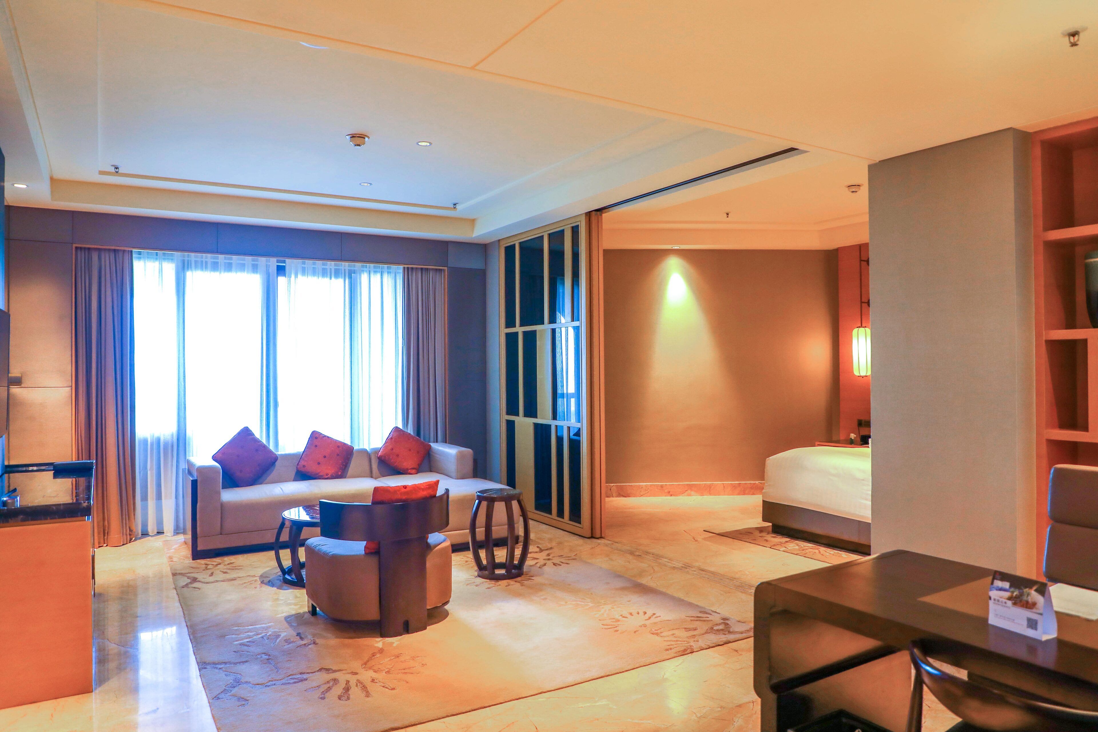 A hotel room with a sofa, armchair, coffee table, and a bed.