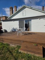 Una casa con terraza, chimenea y puerta corrediza de vidrio.