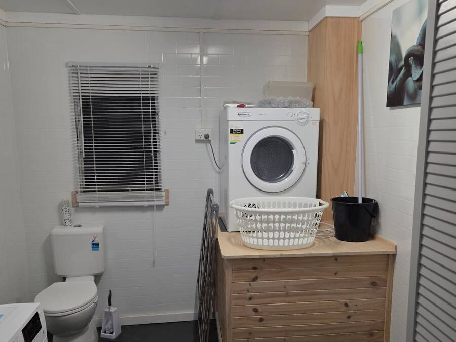 Een kleine wasruimte met een wasmachine, een droogrek en een klein houten aanrecht.