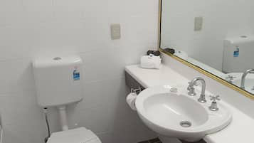 Une salle de bain avec des toilettes, un lavabo et un miroir.