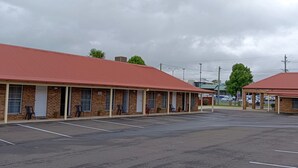 Un motel con una hilera de habitaciones, cada una con techo rojo y fachada de ladrillo.