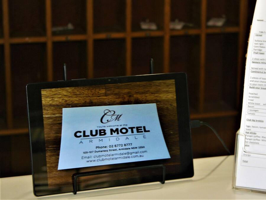 Menú de desayuno del Club Motel Armidale sobre un atril, con fondo de madera.