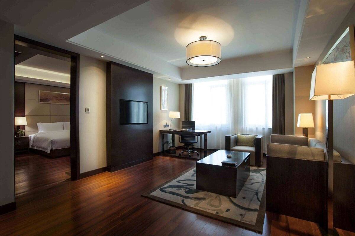 Une chambre d’hôtel équipée d’un lit, d’un bureau, d’une chaise, d’une table basse et d’un téléviseur.