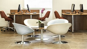 A modern office with ergonomic chairs, desks with computers, and a decorative orchid plant. - Ibis Rio de Janeiro Parque Olimpico (Rio de Janeiro)