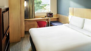 A hotel room with a bed, a desk, a chair, and a window with curtains. - Ibis Rio de Janeiro Parque Olimpico (Rio de Janeiro)