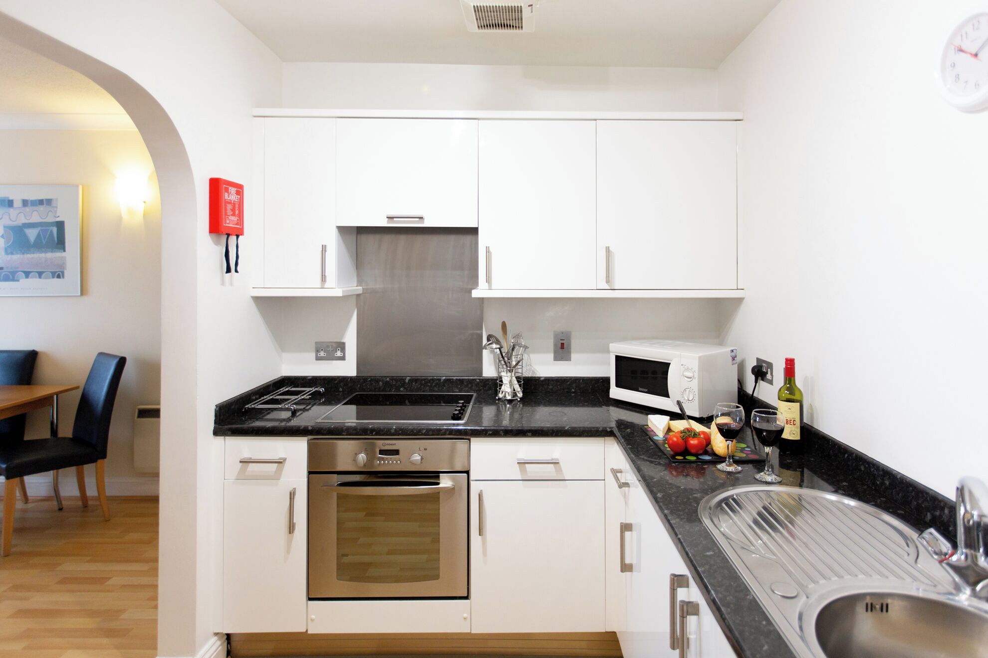 A modern kitchen with white cabinets, a stainless steel oven, a microwave, and a sink.