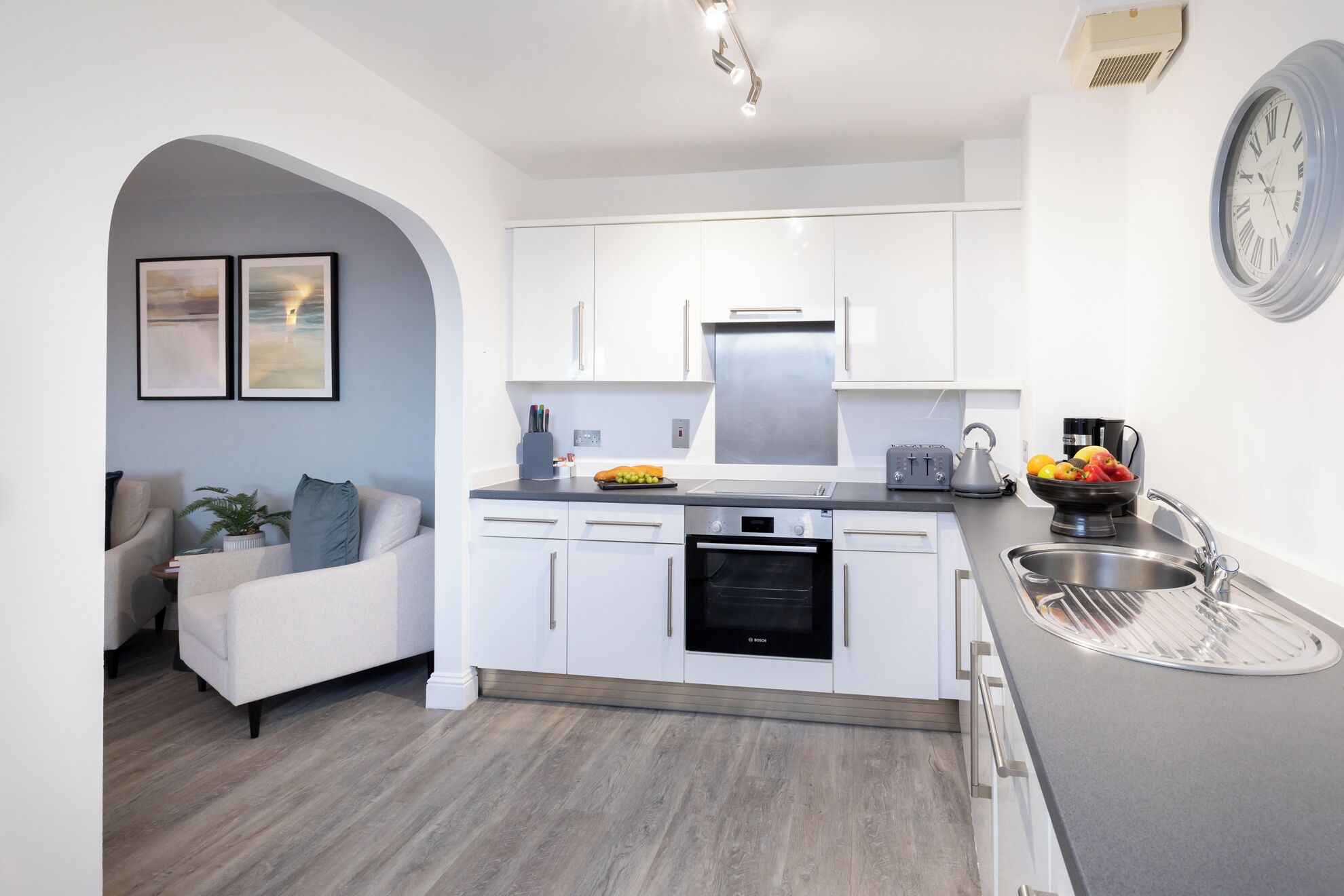 A modern kitchen with white cabinets, a Bosch oven, and a sink.