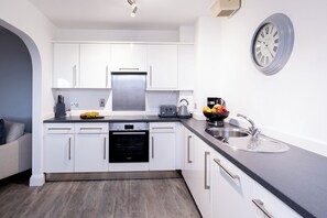 A modern kitchen with white cabinets, a Bosch dishwasher, a toaster, and a sink. - SACO Jersey Merlin House (St. Helier)