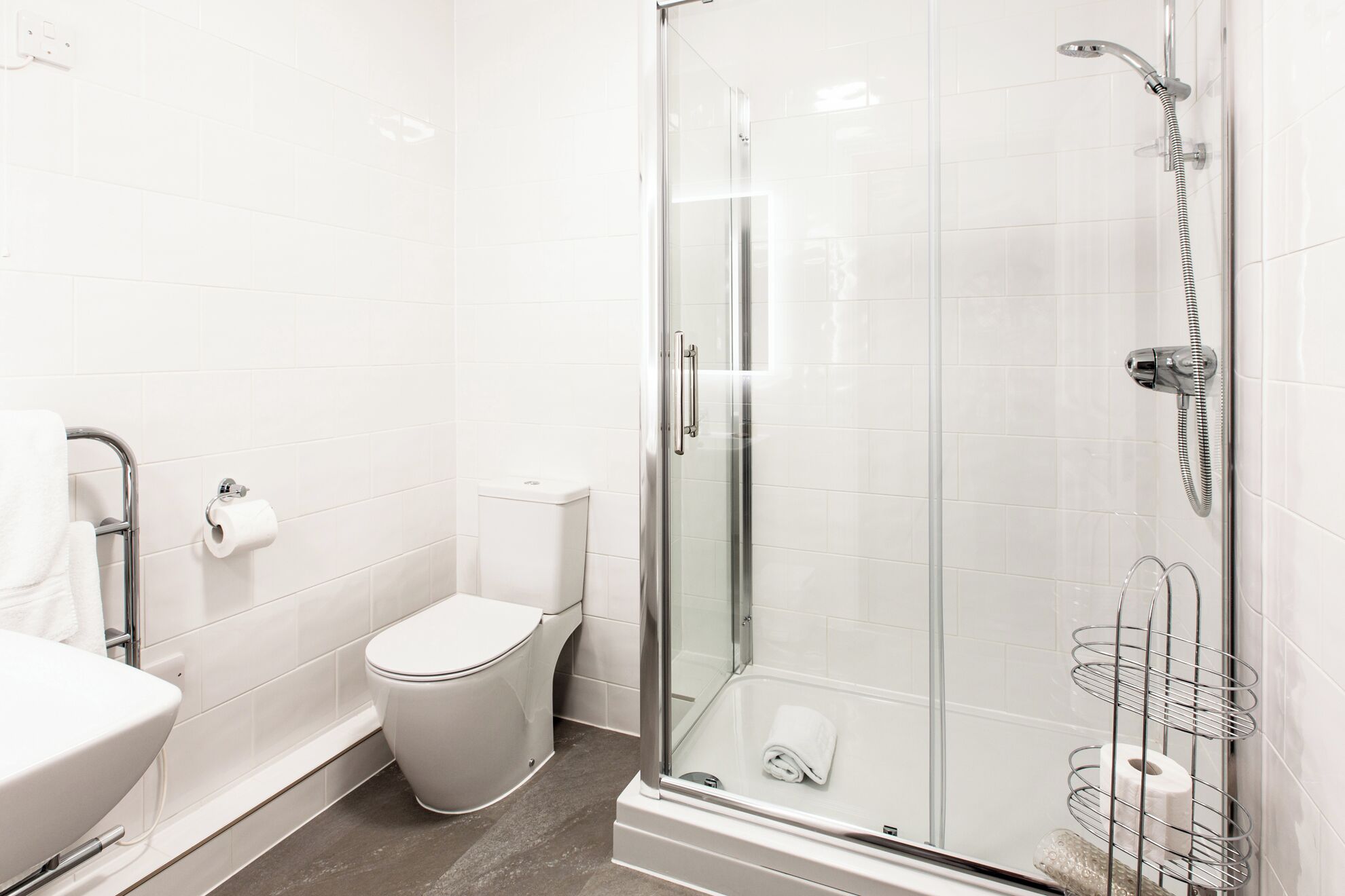 Een moderne badkamer met een douchecabine van glas, een toilet en een wastafel.