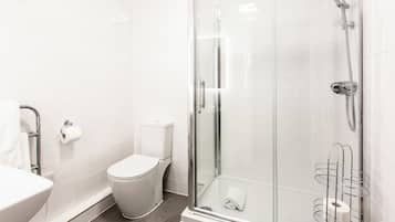 Een moderne badkamer met een douchecabine van glas, een toilet en een wastafel.
