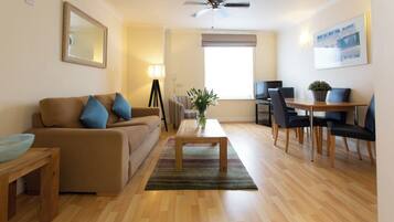 A living room with a sofa, coffee table, and a dining area with chairs and a table.