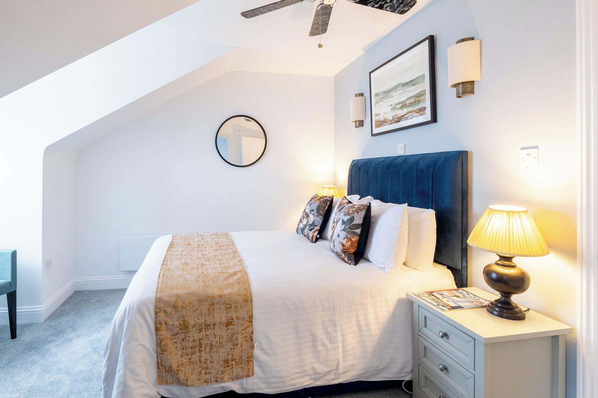 Ein Schlafzimmer mit Bett, Nachttisch, Lampe und Deckenventilator.