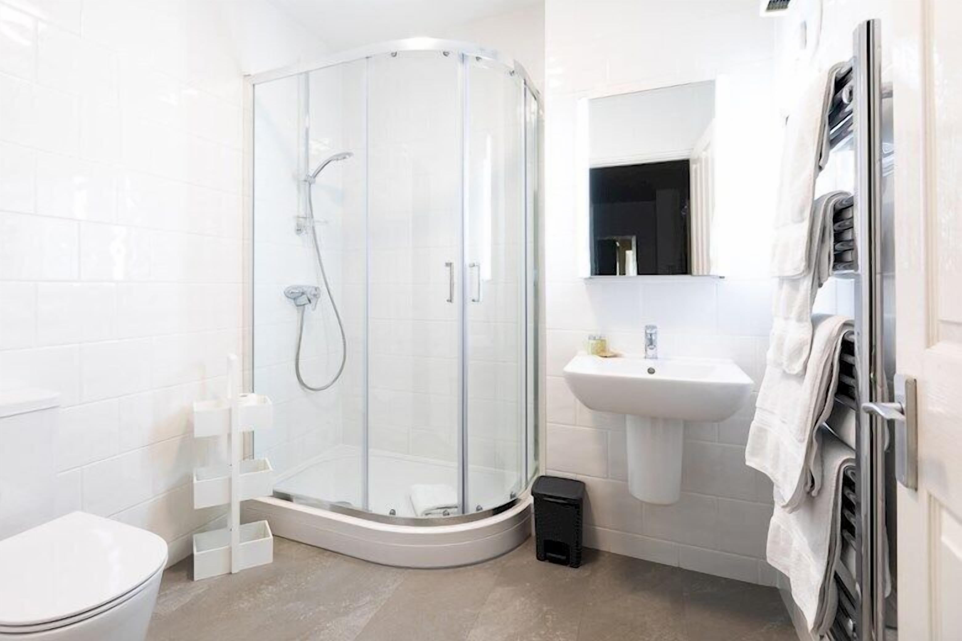 A modern bathroom with a glass-enclosed shower, a white sink, and a toilet.