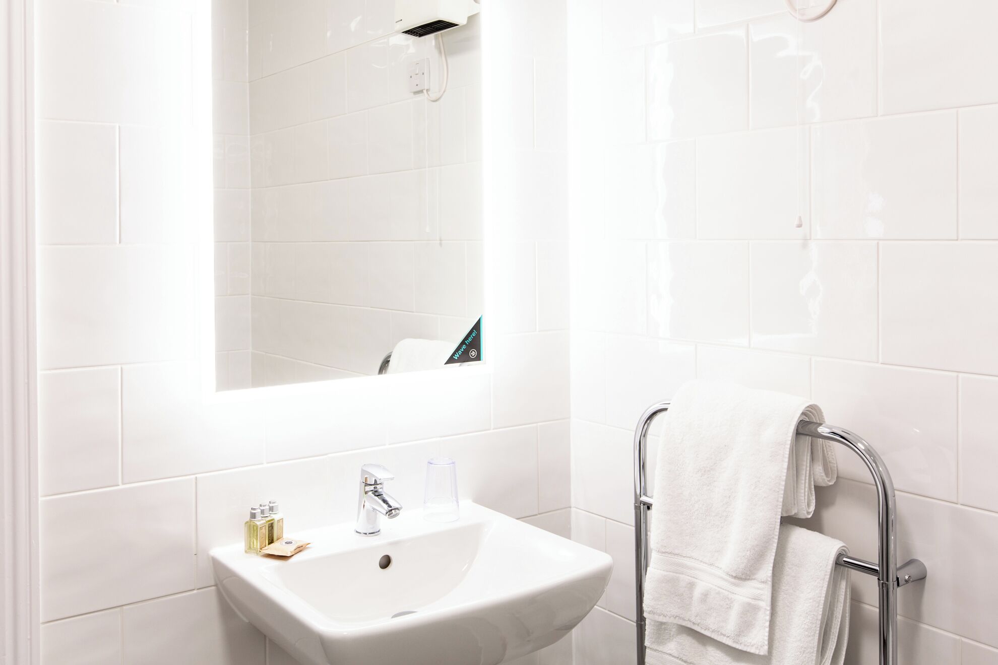 A bathroom with a white sink, a mirror, and a towel rack.