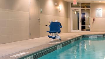 Zona de piscina con tabla de clavados, cartel de normas de la piscina y una puerta que da a otra habitación.