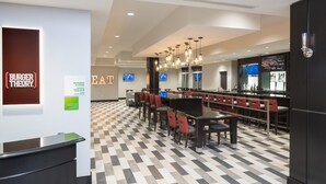A modern restaurant with a checkered floor, multiple seating areas, and a bar. - Holiday Inn Indianapolis Airport by IHG (Indianapolis)