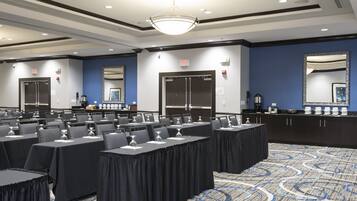 A conference room with tables, chairs, and a buffet area.
