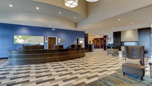 A hotel reception area with a modern design, featuring a reception desk, seating area, and a patterned floor. - Holiday Inn Indianapolis Airport by IHG (Indianapolis)