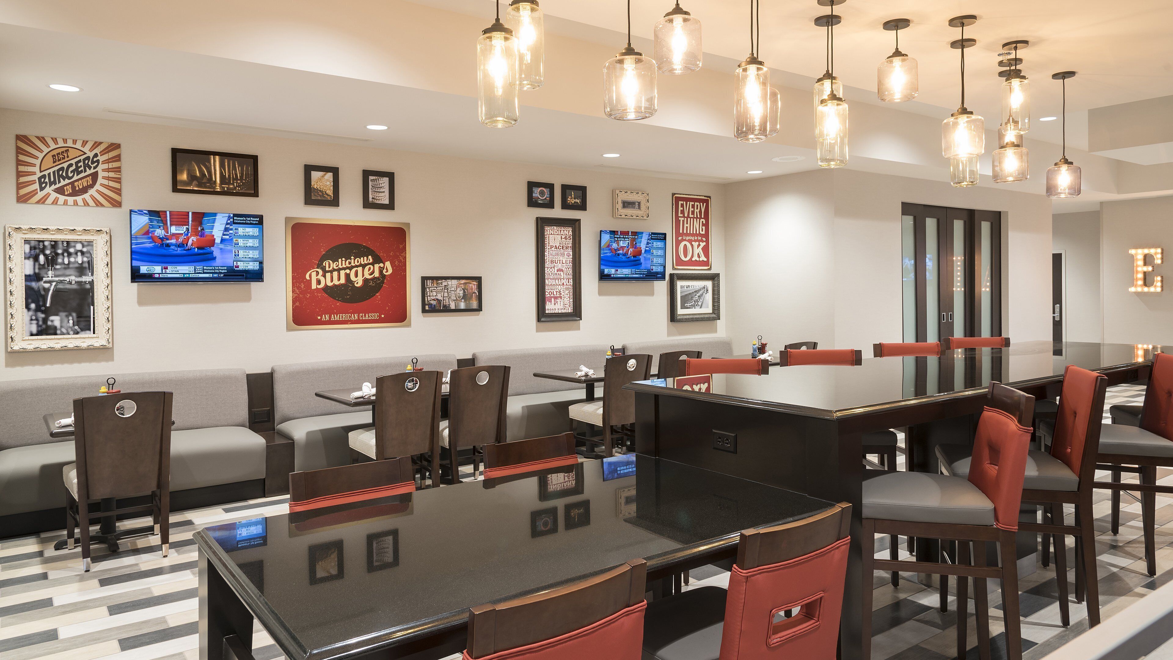 A restaurant with booths and tables, hanging light fixtures, and various framed pictures on the walls.