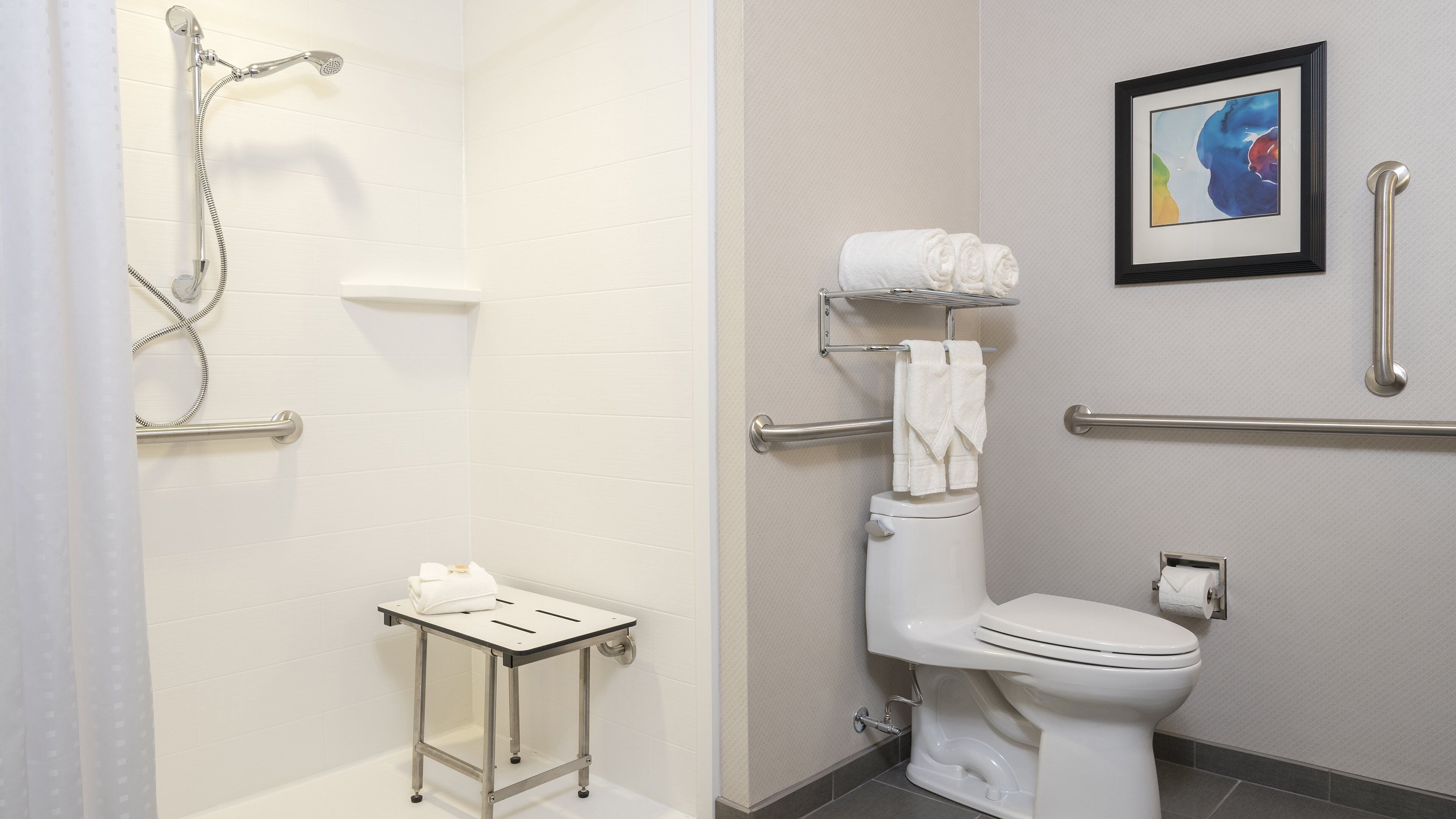 Een badkamer met douche, toilet en een klein tafeltje met een handdoek.