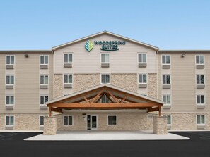 A hotel with a stone facade, multiple windows, and a central entrance with a wooden canopy.