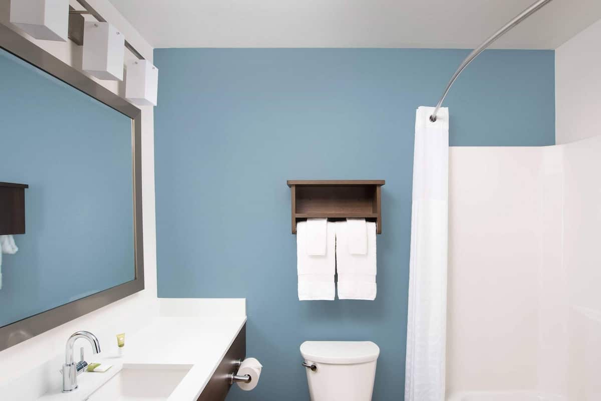 A bathroom with a white sink, a toilet, a shower curtain, and a towel rack.
