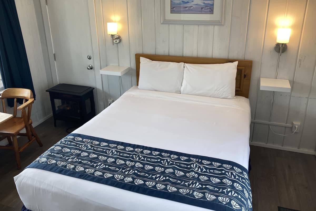 A neatly made bed with a patterned bedspread, a wooden headboard, and two bedside lamps.