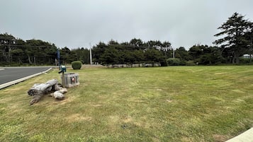 A grassy area with a curb, a blue sign, and a wooden structure.