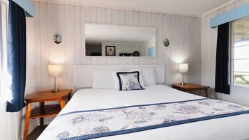 A bedroom with a large bed, a nightstand, a mirror, and a window with curtains.