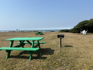 A picnic area with green benches and a black mailbox, overlooking a beach. - Tillicum Beach Motel (Deane's Oceanfront Lodge) (Yachats)