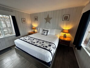 A neatly arranged bedroom with a large bed, two bedside tables with lamps, framed pictures on the wall, and a star decoration above the bed. - Tillicum Beach Motel (Deane's Oceanfront Lodge) (Yachats)
