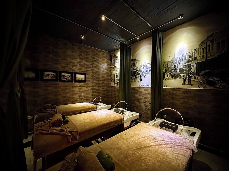 A hotel room with two beds, a brick wall, and a mural of a historical scene.
