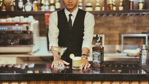 Un cantinero detrás de la barra, con una botella de Jack Daniel's y una copa de martini sobre el mostrador.