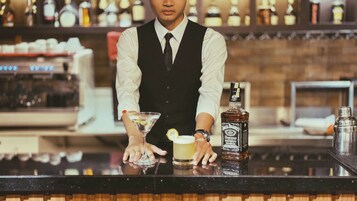 Een barman achter een bar, met een fles Jack Daniel's whisky en een martini glas op de toonbank.