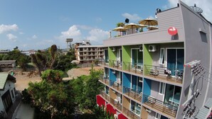 A multi-story hotel with balconies, outdoor seating, and a view of the beach. - Cheeky Monkey's Samui (Koh Samui)