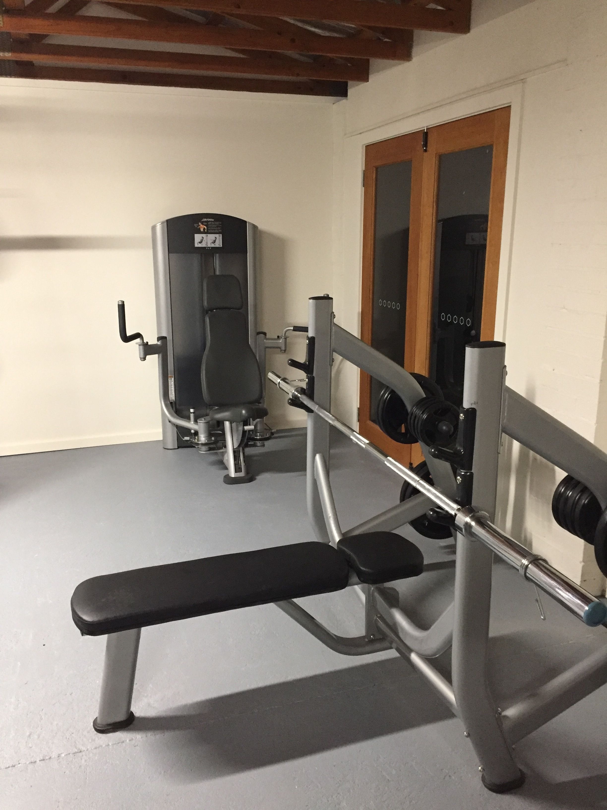 A gym with a bench press, a squat rack, and a weight bench.