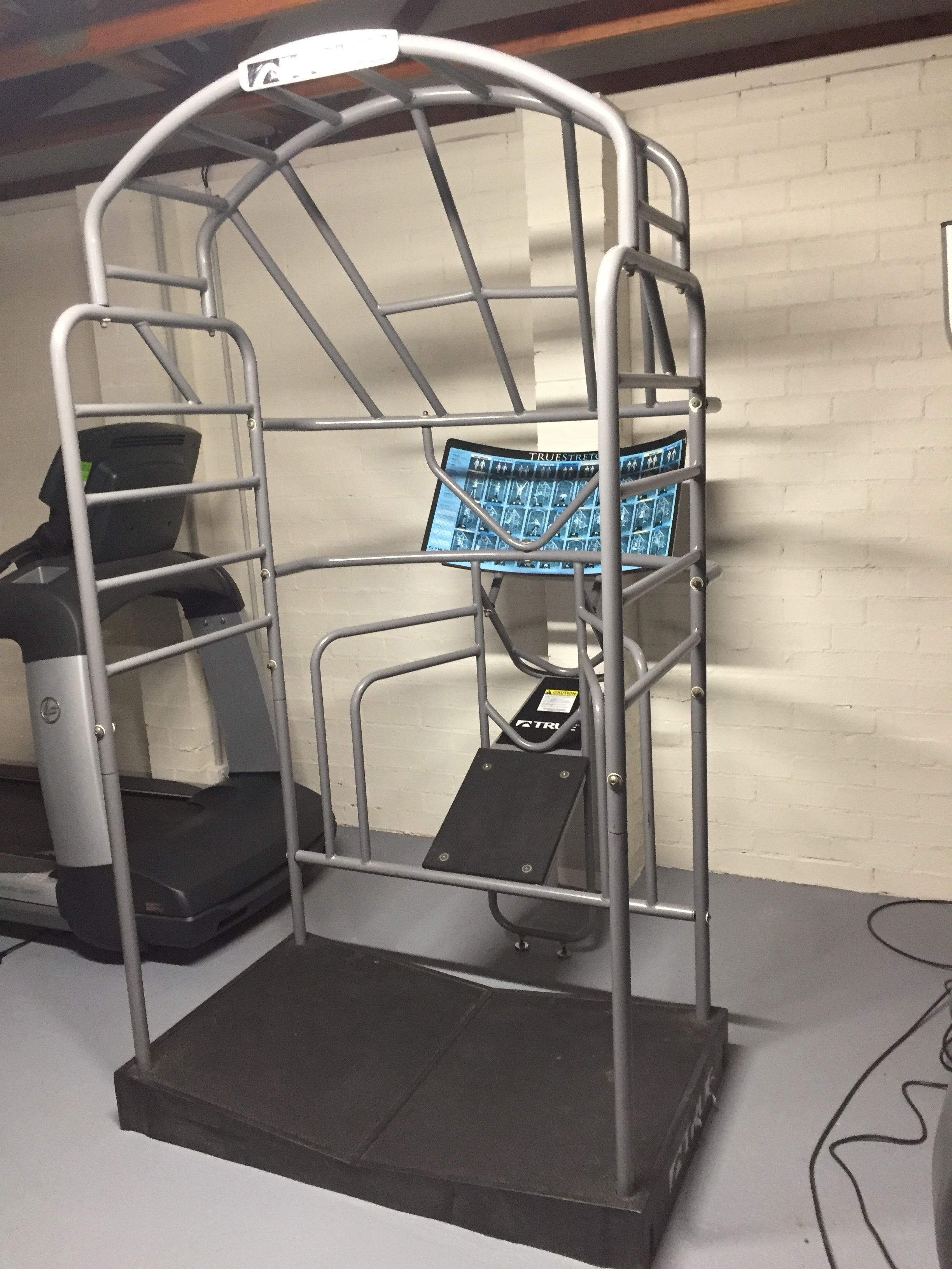A gym with a treadmill, a multi-tiered weight bench, and a digital display.