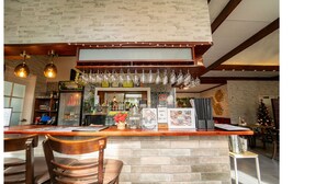 A bar area with a brick wall, wooden ceiling beams, hanging light fixtures, and a Christmas tree.